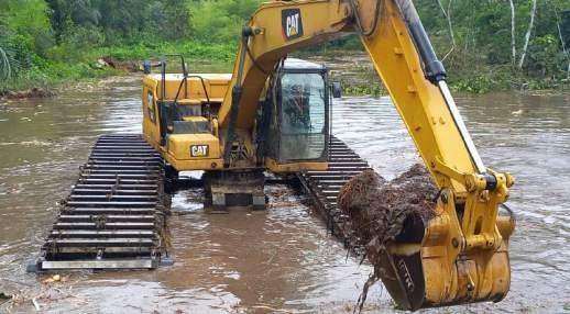 Amphibious excavator desilting a blocked waterway